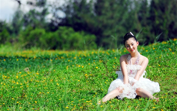 Menina asiática que senta-se na grama Papéis de Parede, imagem