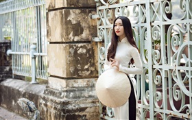 A menina asiática, vestido branco, cabelo longo, cerca