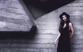 Menina preta do vestido, chapéu, parede