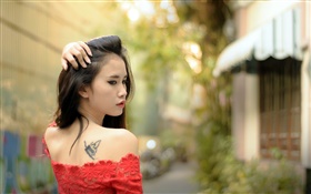 A menina asiática, tatuagem, vestido vermelho, olhar para trás