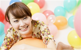 A menina asiática feliz, balões coloridos