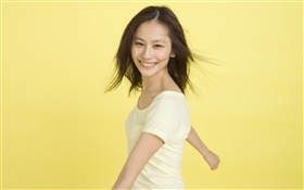 A menina asiática feliz, fundo amarelo