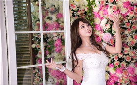 Sorriso asiático da menina, vestido branco, flores fundo